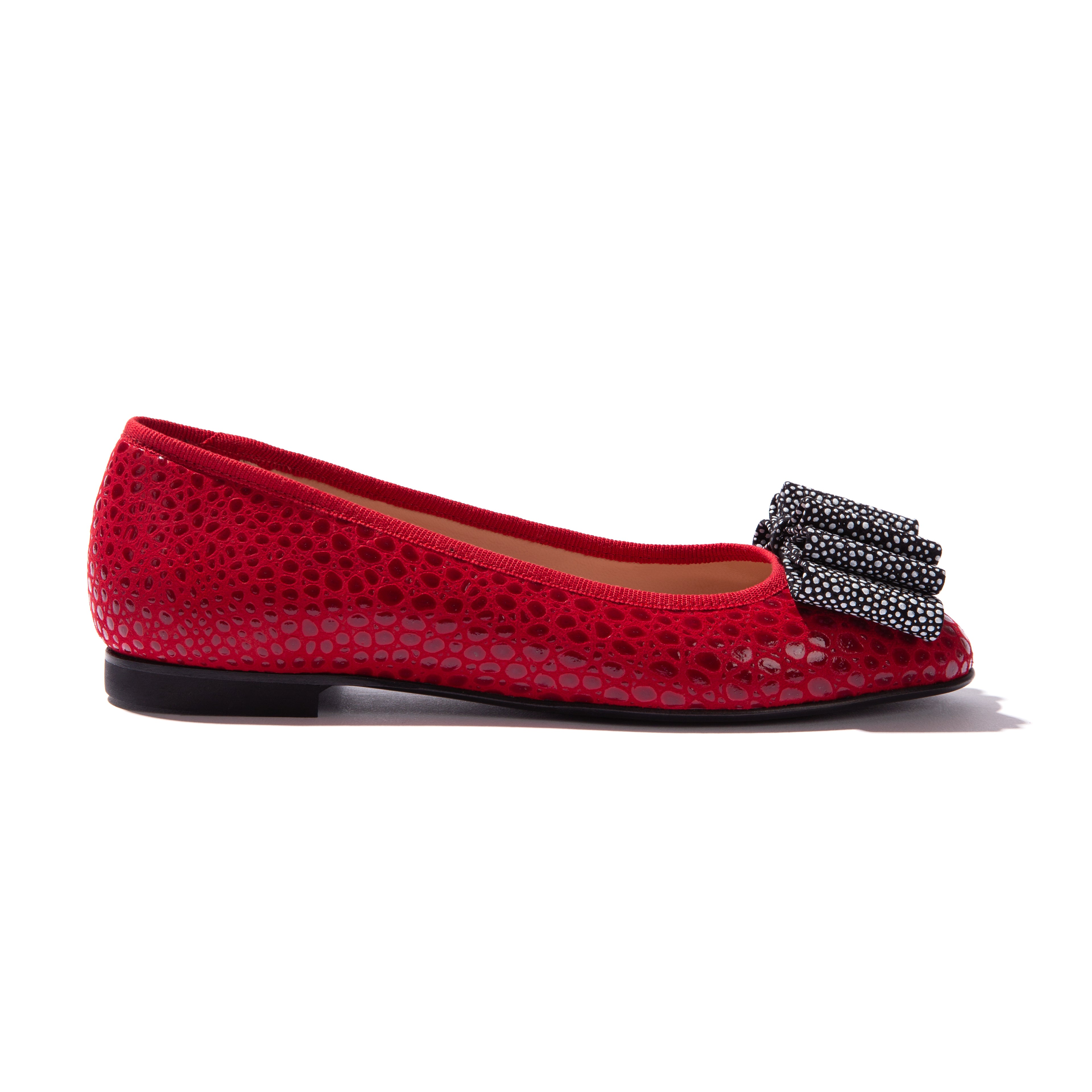 A red ballet flat with a ladybug detail on the upper part of the shoe.